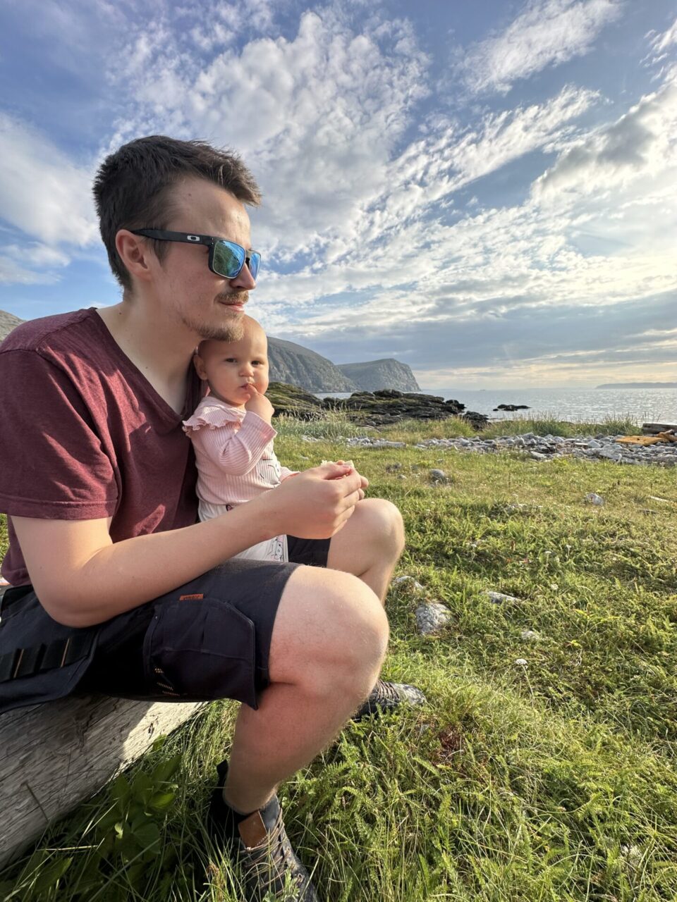 Far og datter som sitter i fjæra